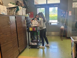 Students in art class at Wilsonville High School gather materials from the supply cart as they prepare to start their projects. Creativity is in full swing as the classroom buzzes with color!