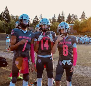 Football athletes Trevor Glos, Rhett Smith, and Ryder Barclift pose for a picture during warmups. While the sun sets on the pink-out themed homecoming game, the Wildcats get in the zone to defeat Forest Grove. 