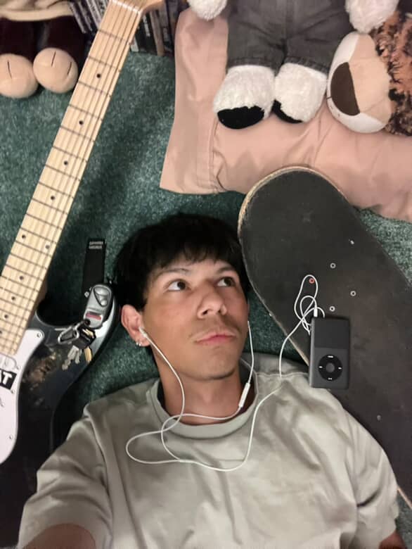 Mario Ulloa surrounded by the things he loves guitar, skateboard, and music 