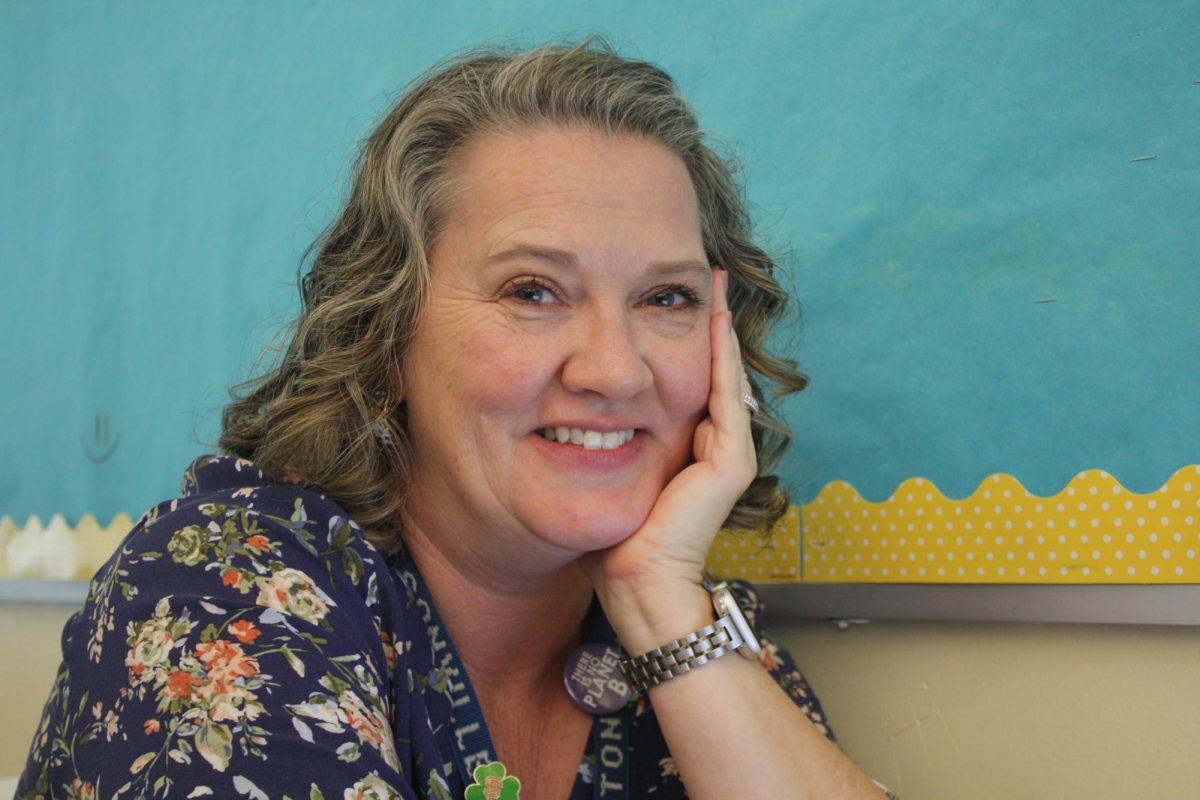 Mrs. Heaton, a tenth grade English teacher, poses in her classroom. She smiles warmly, a symbol of her joy that she carries with her teaching. 