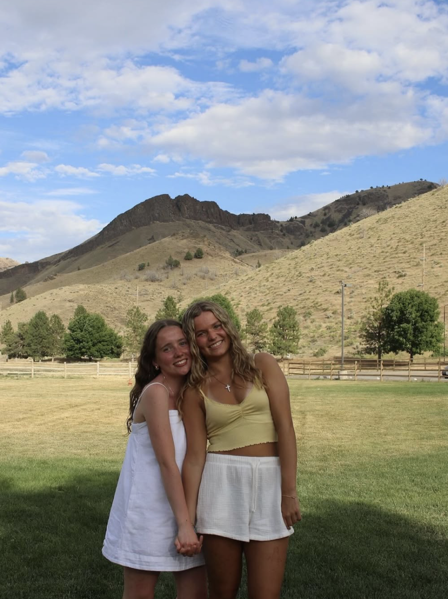 Andrea Ormsby in her clearly white dress smiles with her friend at YoungLife camp. Andrea adventures to camp every summer in eastern Oregon.