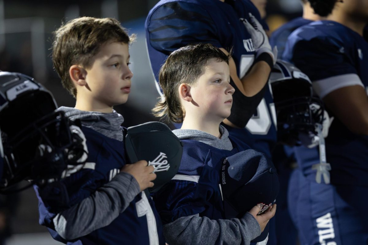 During the playing of the National Anthem, Andrew and Nathan Swan remove their caps and place their hands over their hearts. As Wilsonville's Junior Wildcats, they will get to spend the entirety of the game alongside the Varsity team on the sidelines. 