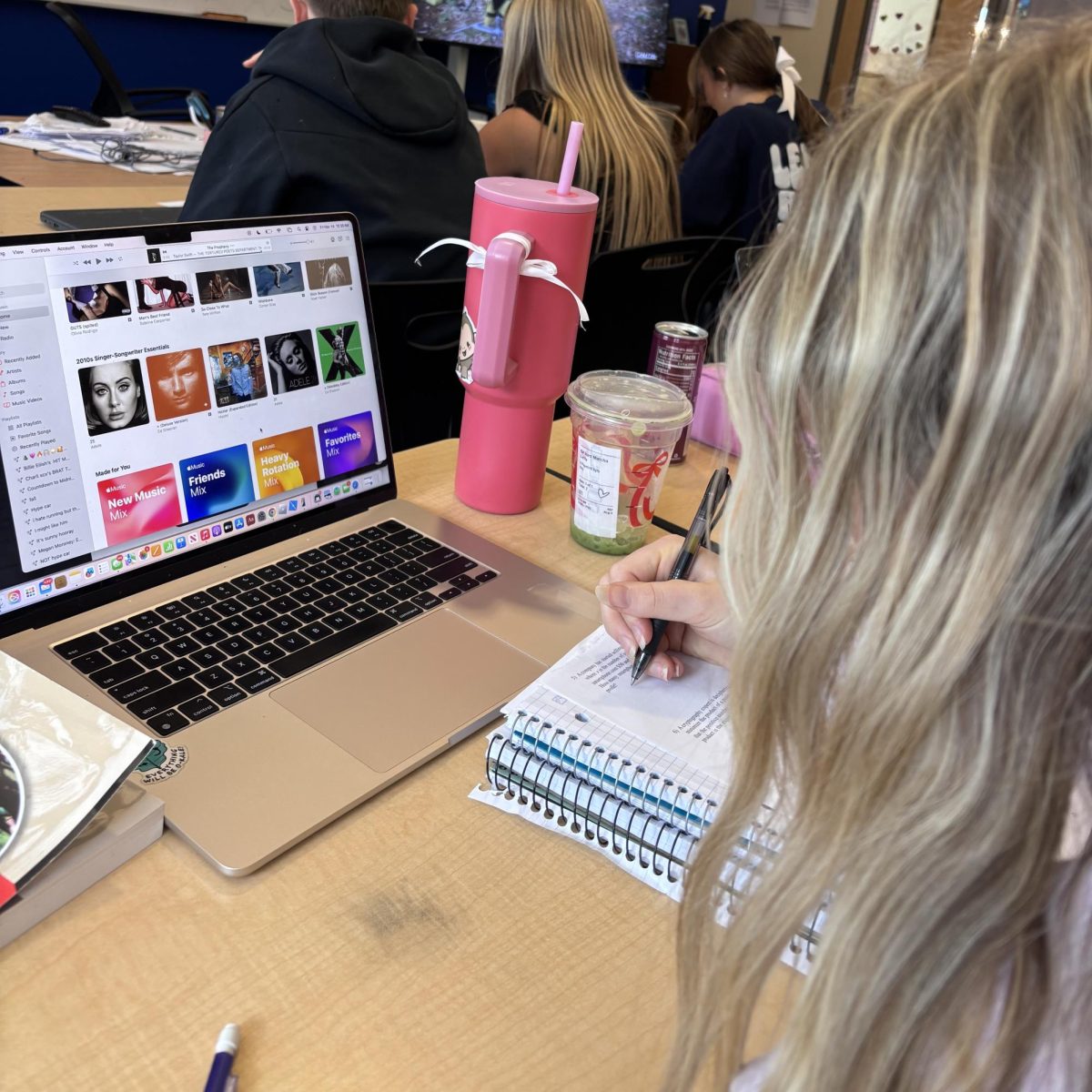 Senior Olivia Clark writes notes in her notebook while studying for her Calc test. She listens to music such as Sabrina carpenter while she studies.