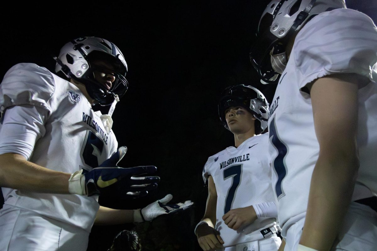 Number 5 on Wilsonville's varsity football team, Brock Taylor, convenes with junior quarterback, Trevor Gloss on the sidelines of a home game against Canby. Discussing or debating, many athletes interact with one another during game time, but the conversations remain respectful and positive. 