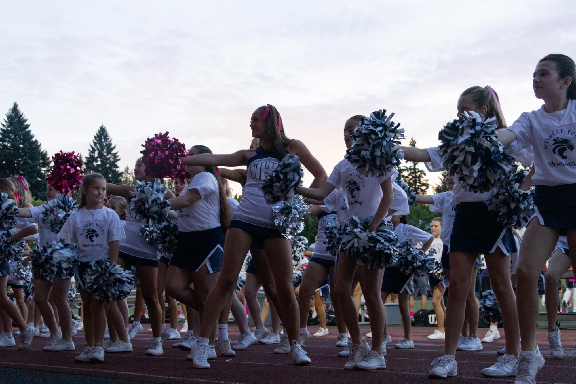 Varsity cheerleaders blend with Wilsonville's youth cheerleaders during a home football game. Energizing the crowd, the cheerleaders work hard to lead with joy and confidence. 