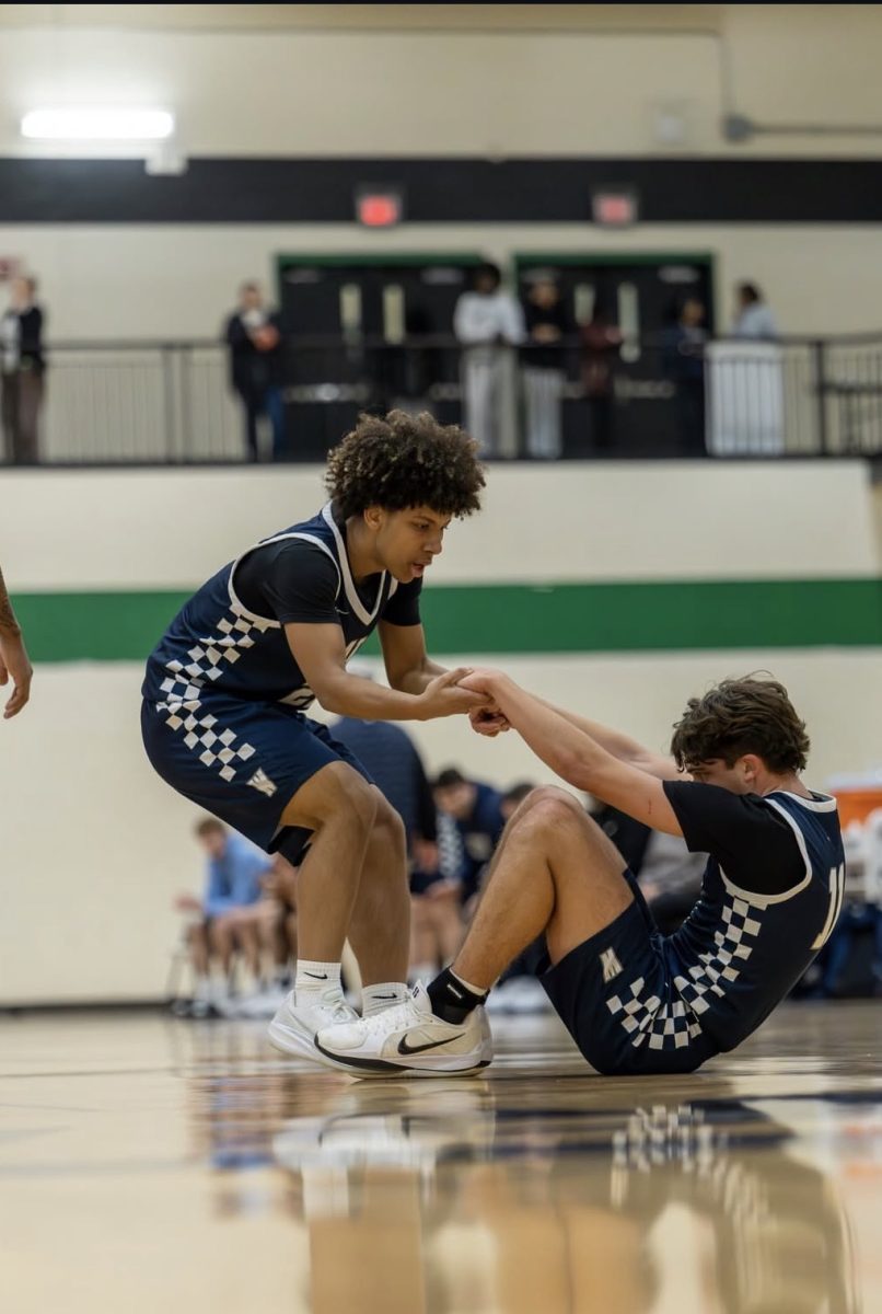 Junior guard Will Maina helps up fellow junior guard Jett Bruce.