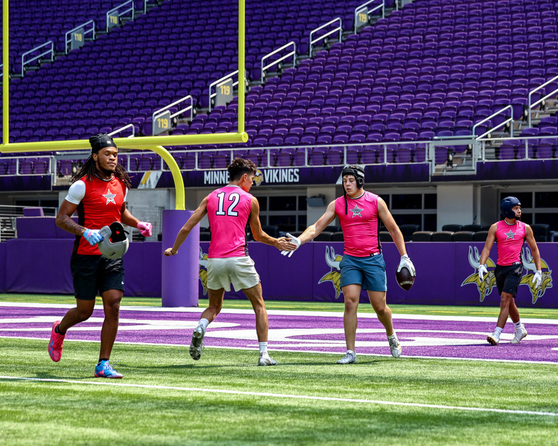 Wilsonville Quarterback Trevor Glos high fives teamate in a 7 on 7 tournament at US Bank Stadium. 7 on 7 games and tournaments are very beneficial for football players improving on routes and coverage staying share during the offseason