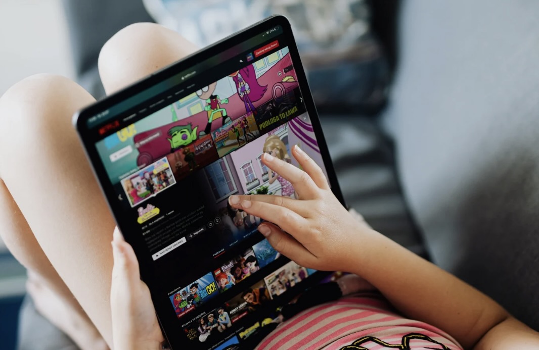 Image of child scrolling on their Ipad searching for something to watch. children who are given constant access to screens have a difficult time being comfortable with being bored. 