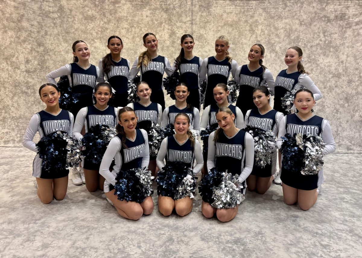 Before performing, Wilsonville cheerleaders gather for a team picture. Dressed down in uniform and topped with pom-poms, the Wildcats ready their smiles for game time. 