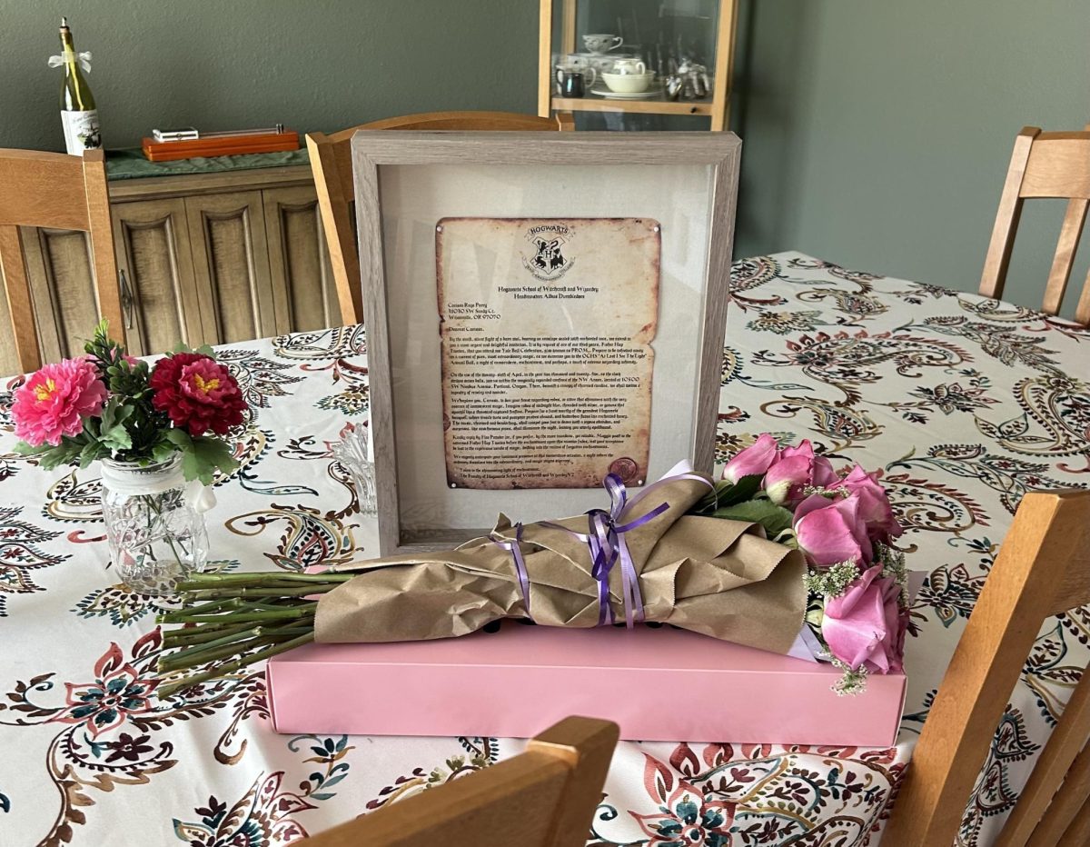 Photo of a gift including a box of cookies and flowers sitting in front of a handwritten note as a prom proposal. Oftentimes handmade gifts are more thoughtful than those we buy from the store.
