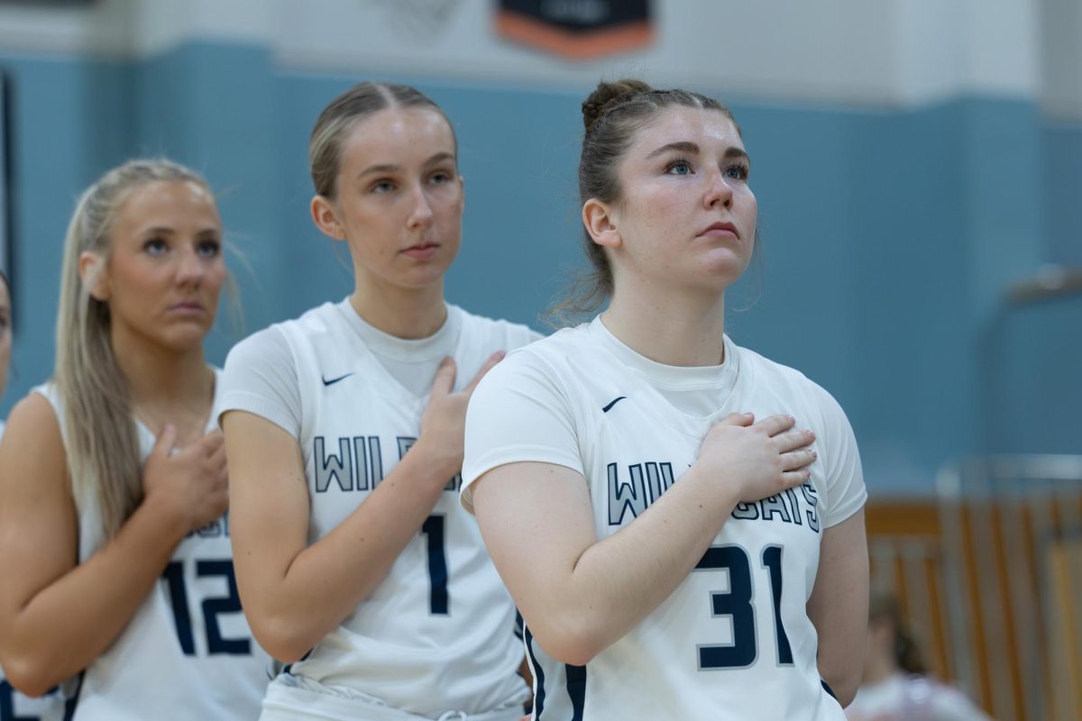 Gabi Moultrie, Maylin Brogren and forward Addi Smith look at the flag during the national anthem right before tip-off against Canby. Wilsonville would go on to win 79-33.