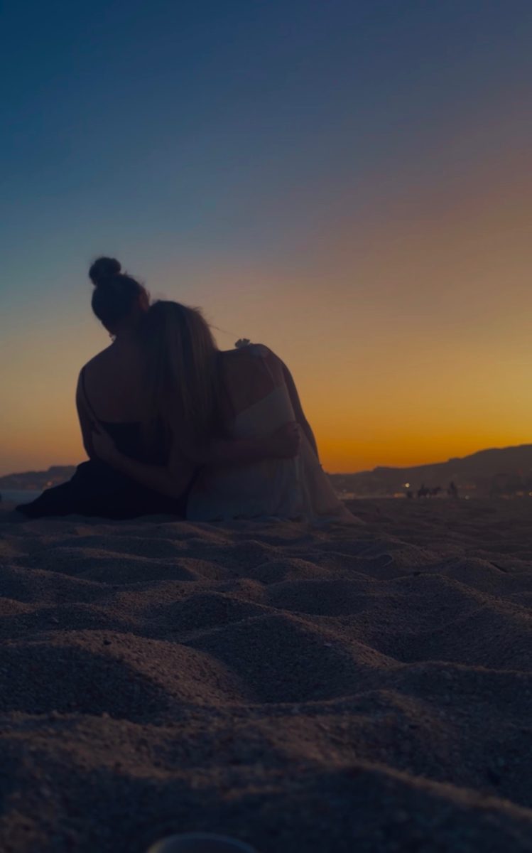 Sisters, Cait and Avery Eckley, sit on the beach of Cabo, Mexico as the sunset fades before them. In the soft sillohette of the evening, the two share a sentimental moment of embrace. 
