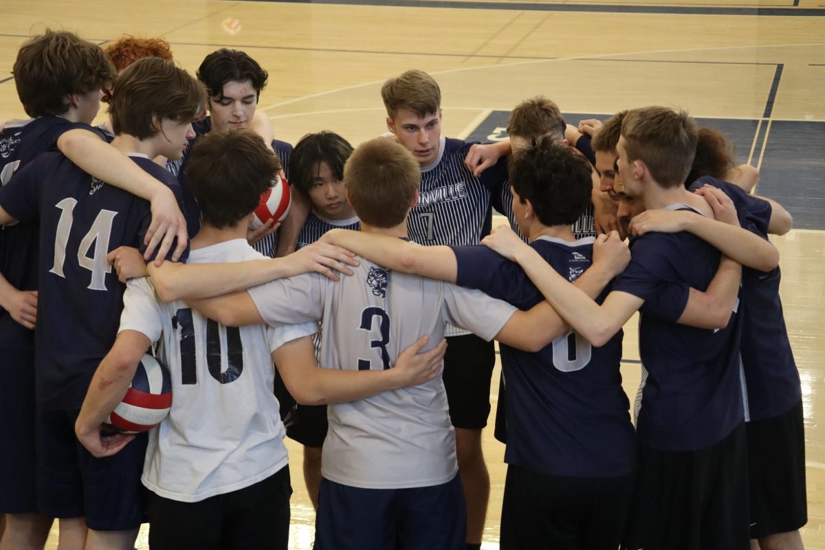 Pictured, is a photo taken at the home opener for the boys volleyball team against Sherwood. The guys huddle at a timeout to strategize. 