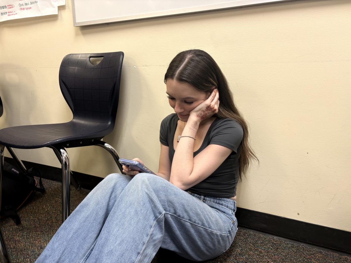 Image shows a teen "doom scrolling" on her phone. This image illustrates how It can start as one quick check, and turn into hours of swiping - trapped in the false reality that is social media.
