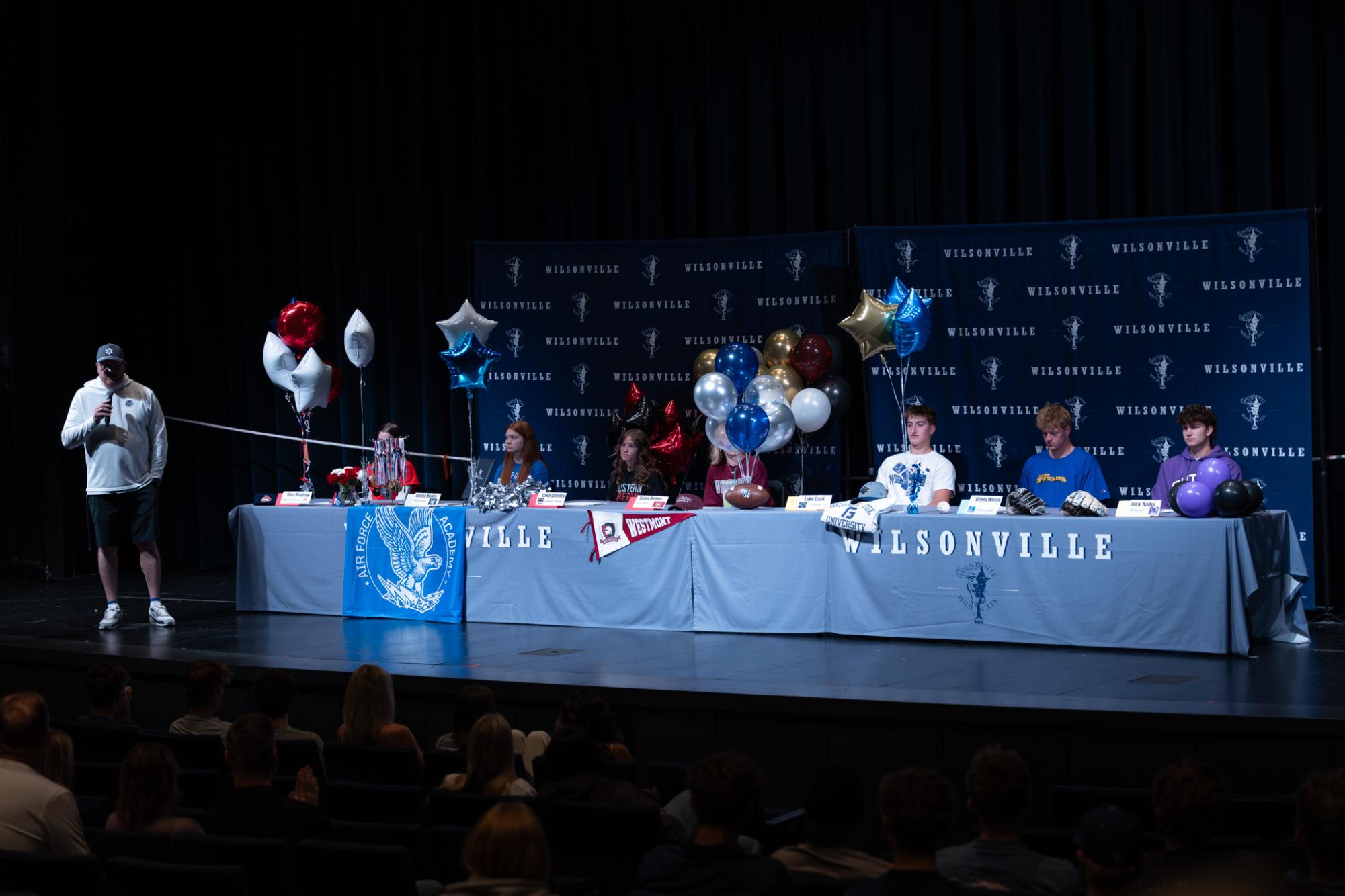 All seven athlete sit at their signing tables. Singing day was hosted on May 12, 2026 in Wilsonville High school's Performing Arts Center.